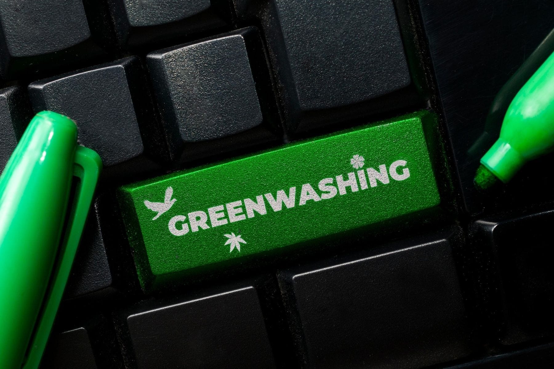 Green key on a black keyboard says ‘greenwashing.’ The key is surrounded by green markers