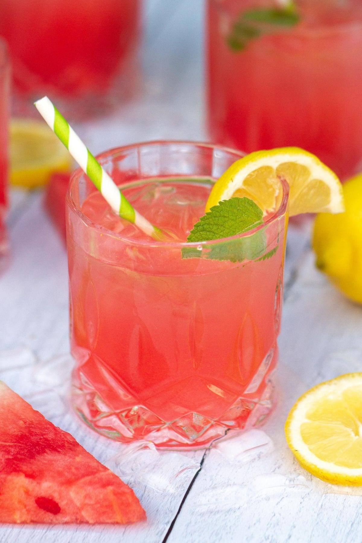 A glass of watermelon lemonade with a fresh mint leaf.
