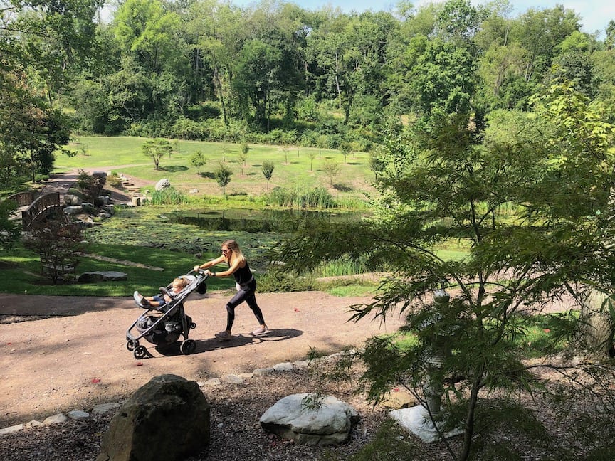 A woman pushes a stroller while walking through a botanical garden.