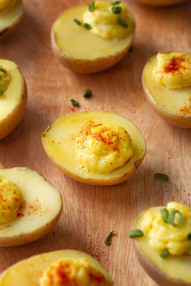 Half baby potatoes filled with creamy, vegan deviled filling, sprinkled with paprika and chives.