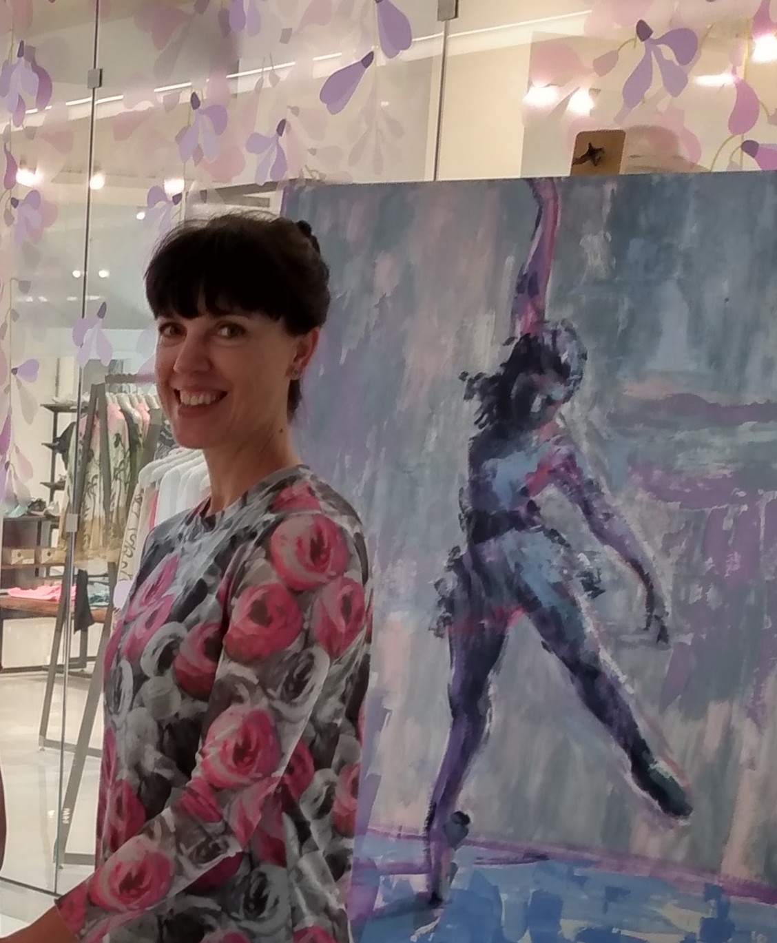 Photo of artist Claire Hardy with one of her paintings of a ballet dancer