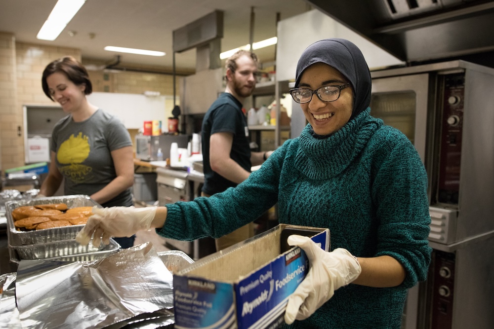 412 Food Rescue. Benter Foundation photographs Following food donated earlier in the day from CMU to the First Presbyterian Church on 6th Street for an evening meal sponsored by OutreachedArms.org. Maryem Aslam front, helps prepare the food for the evening meal. Backgroun: Daniel Snyders and Leslie Turis